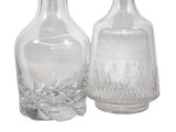two clear glass bottles sitting next to each other on a white surface