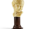 un gros plan d'une sculpture représentant la tête d'un enfant posée sur un socle en bois