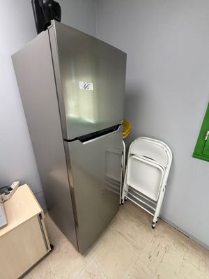 un réfrigérateur argenté à côté d'une chaise blanche dans une pièce