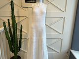 une robe blanche posée sur un mannequin, à côté d'un cactus en pot