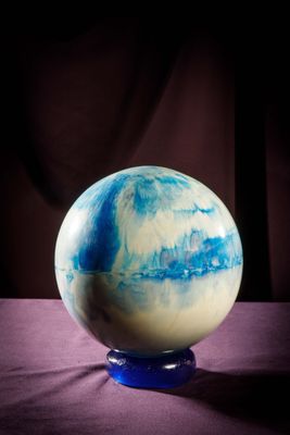 une sphère en marbre bleu et blanc posée sur un tissu violet
