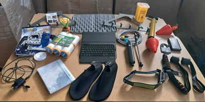 un bureau sur lequel se trouvent un ordinateur portable, un clavier, une souris, un casque et d'autres objets