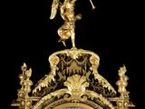 a gold clock with a statue on top of it