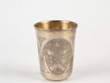a silver cup with a design on it on a white surface