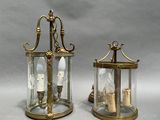 pair of brass and glass lanterns with candles inside of them