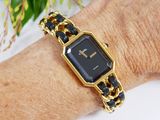 a woman wearing a gold and black watch on her wrist
