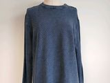 a blue sweater on a mannequin stand against a white wall
