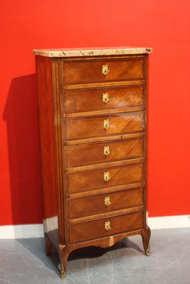 a tall wooden chest of drawers in front of a red wall