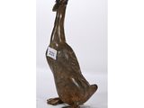 une photo d'une statue de canard en bronze avec une étiquette autour du cou