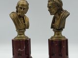 une paire de bustes en bronze représentant un homme et une femme, posés sur des socles