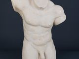 une statue blanche représentant un homme les mains sur la tête