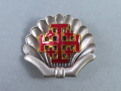 a silver and red brooch with a cross on it