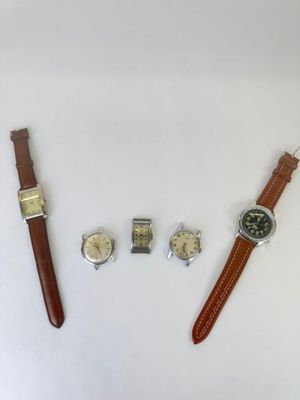 two watches and a wrist watch are sitting on a white surface