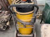 un seau jaune avec un tuyau posé sur un chariot, à côté d'autres objets