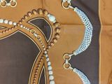 brown and white square scarf with a design of a horse ' s head and beads