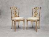 une paire de chaises dorées avec des assises rembourrées sur fond gris
