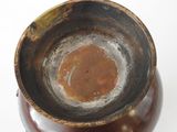 a close up of a brown vase on a white surface
