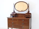 une commode sur laquelle sont posés un miroir et une lampe