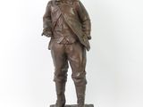 statue en bronze représentant un garçon debout sur un socle, les mains dans les poches
