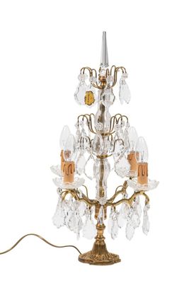 une photo représentant une lampe de table dorée accompagnée d'un lustre en cristal