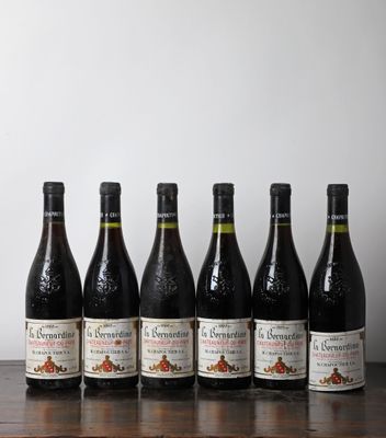 six bouteilles de vin sont alignées sur une table en bois