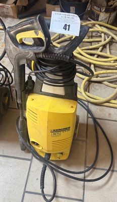 un vérin jaune posé par terre à côté d'une pile d'outils