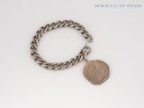 silver chain bracelet with a coin charm on a white background