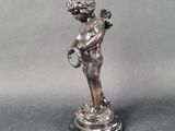 statue of a boy holding a bird on a pedestal on a gray background