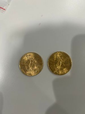two gold coins sitting on top of a white table
