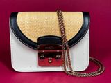a white and black purse with a gold chain on a pink background