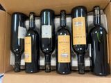 six bottles of wine are in a cardboard box on a table