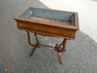 une petite table en bois avec un plateau en verre, posée sur le trottoir