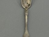 silver spoon on a gray surface with a black dot on it