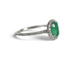 a close up of a ring with a green stone surrounded by diamonds