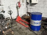 a blue barrel of oil sitting next to a red fork in a garage
