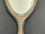 silver plated mirror on a black surface with a reflection of a tear