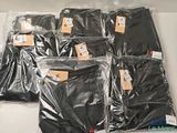 de nombreux sacs contenant des vêtements noirs posés sur une table blanche