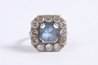 a close up of a ring with a blue stone surrounded by white diamonds