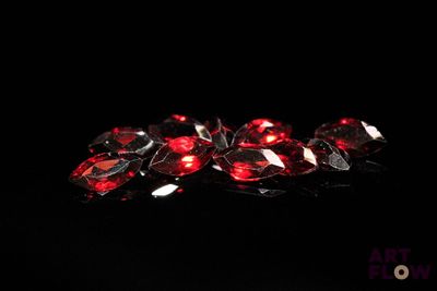 un gros plan sur un groupe de cristaux rouges posés sur une surface noire