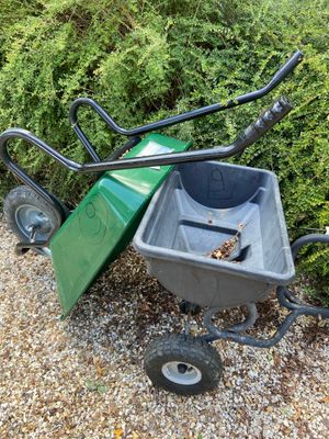 a green wheelbarrow and a black wheelbarrow on a gravel path