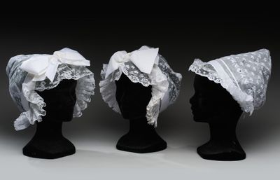 trois têtes de mannequins noires ornées de dentelle blanche et de nœuds