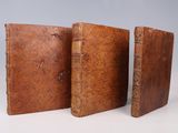 two old leather books sitting next to each other on a white surface
