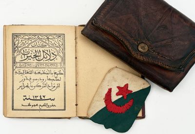 an old book with arabic writing and a leather wallet on a white surface