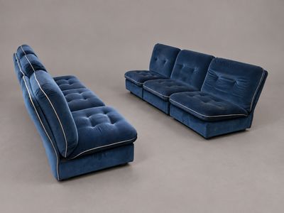 un canapé et un pouf en velours bleu, disposés dans un studio