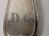 a silver spoon with a dog on it sitting on a table
