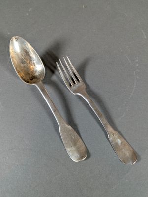 two silver spoons and a fork on a table