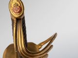 an image of a close up of a gold sword with a red stone on it