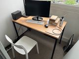 a desk with a computer and a chair in front of a window
