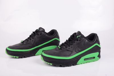 une paire de baskets noires et vertes sur fond blanc