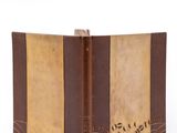 an old book with a brown cover sitting on top of a white surface